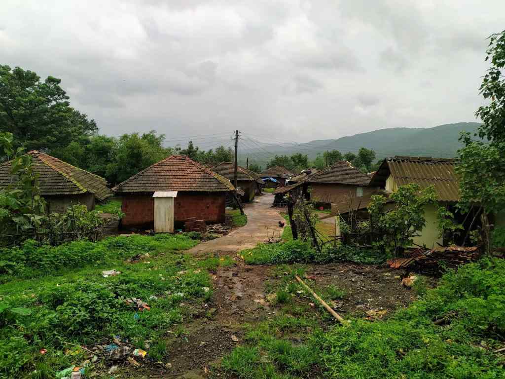 Facecard of Degaon village - huts, foliage and hills