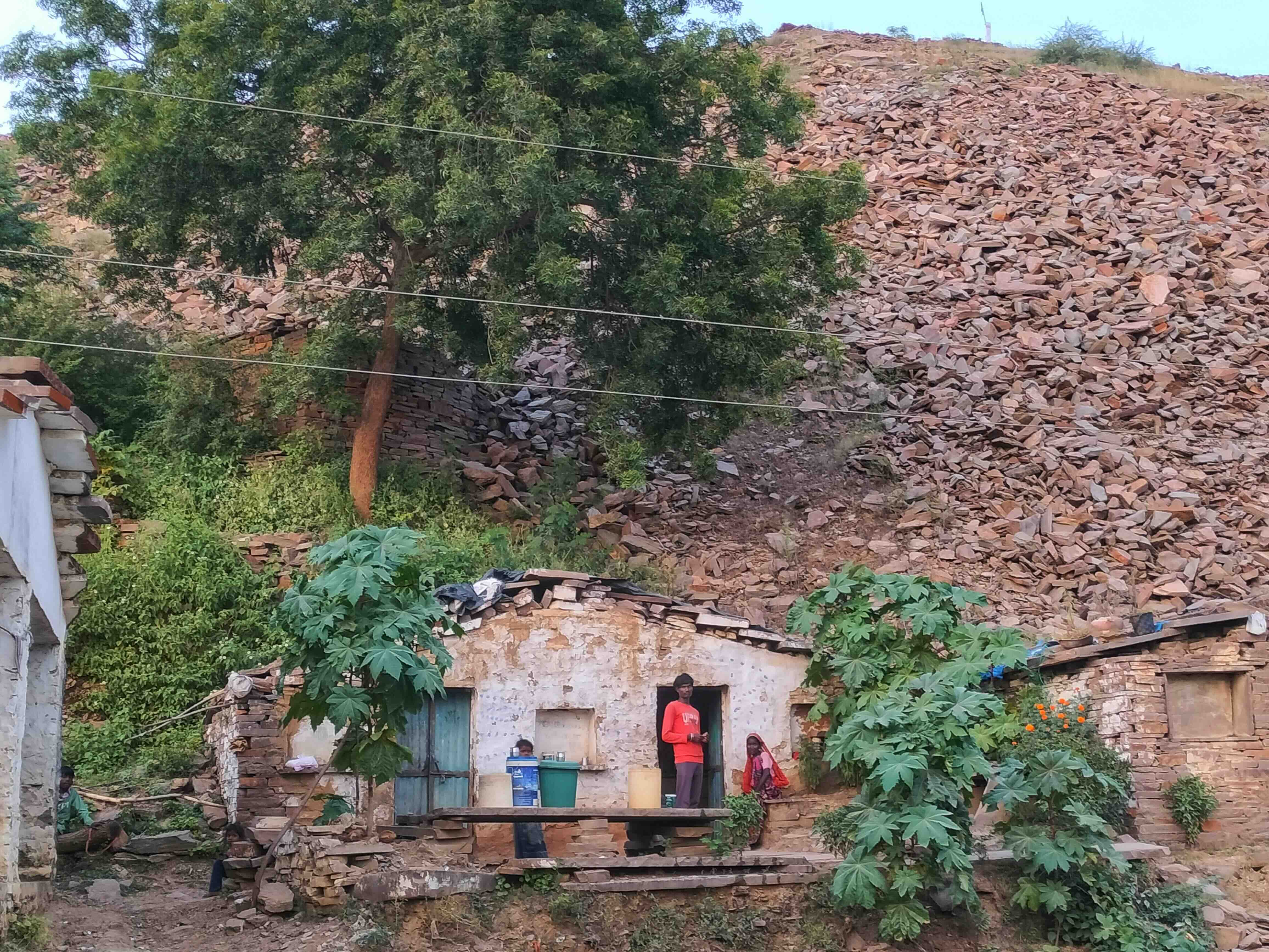 Rural stone house with people in front and mine debris as a hillside behind